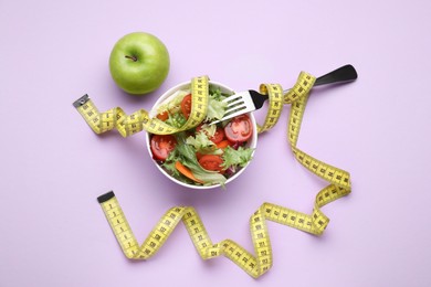 Photo of Bowl with fresh vegetable salad, fork, apple and measuring tape on violet background, flat lay. Healthy diet concept