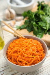 Photo of Delicious Korean carrot salad in bowl on white wooden table