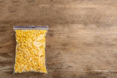 Frozen sweet corn on wooden table, top view with space for text. Vegetable preservation