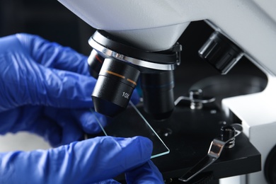 Photo of Medical assistant using microscope at table, closeup