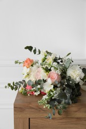Bouquet of beautiful flowers on wooden table near white wall