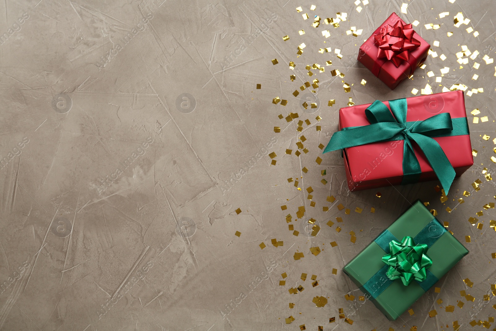 Photo of Gift boxes and shiny confetti on beige textured background, flat lay. Space for text