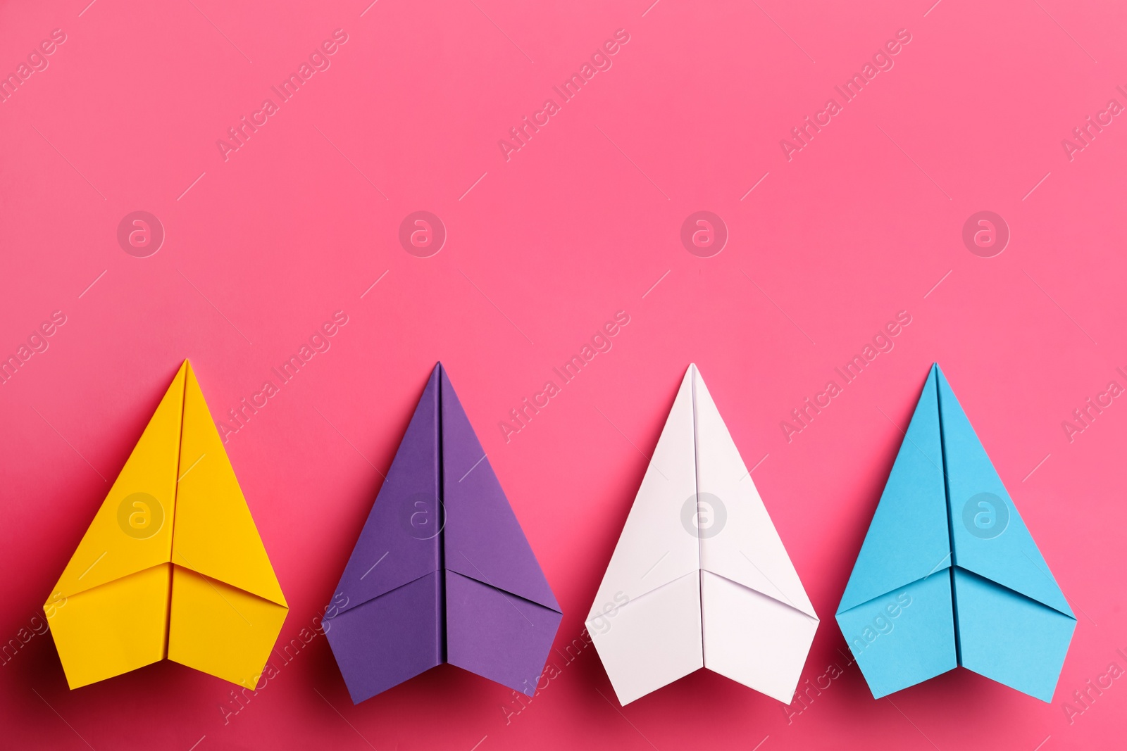 Photo of Handmade colorful paper planes on pink background, flat lay. Space for text