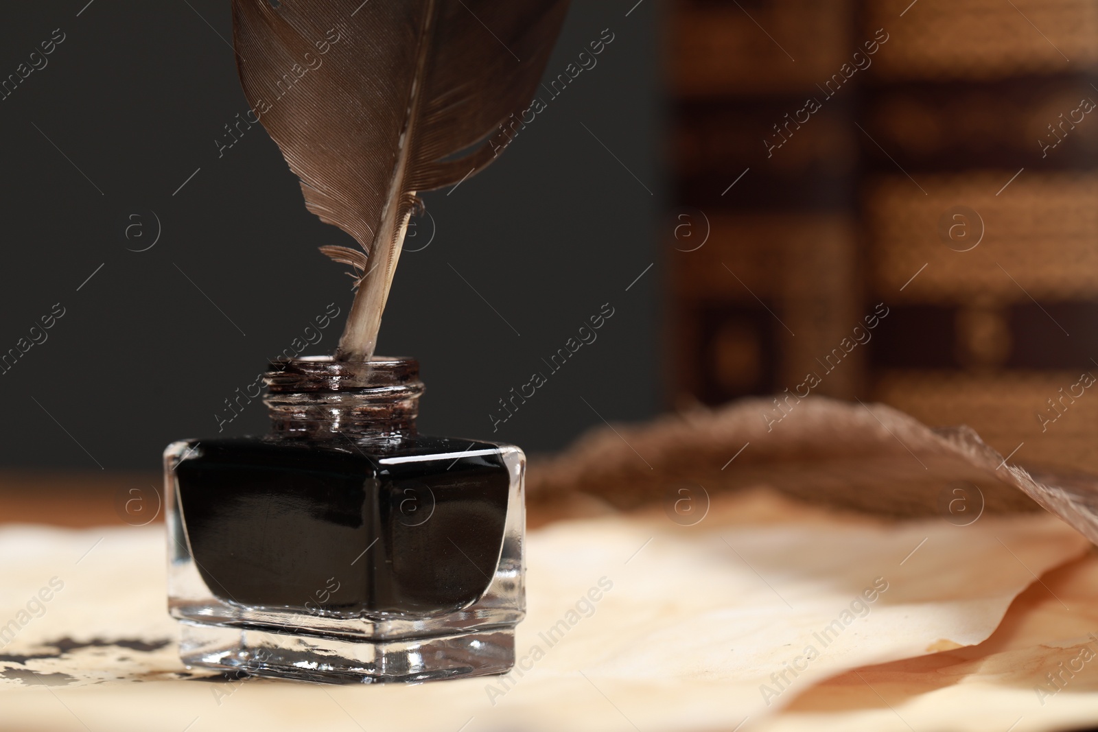 Photo of Inkwell with feather and vintage parchments on table, closeup. Space for text