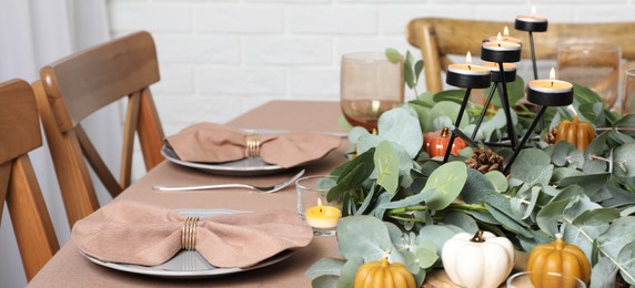 Autumn table setting with eucalyptus branches and pumpkins indoors. Banner design