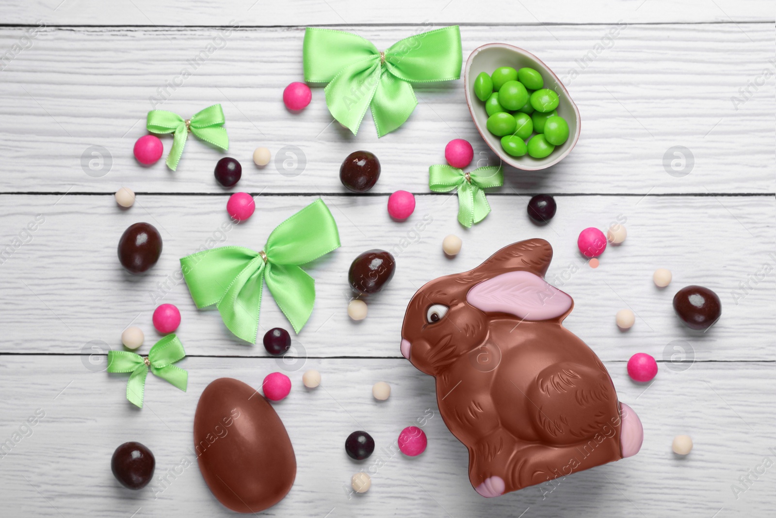 Photo of Flat lay composition with chocolate bunny on white wooden table. Easter celebration