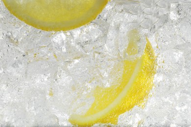 Photo of Juicy lemon slices and ice cubes in soda water against white background, closeup
