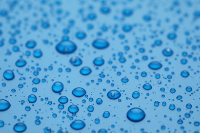 Photo of Water drops on blue background, closeup view