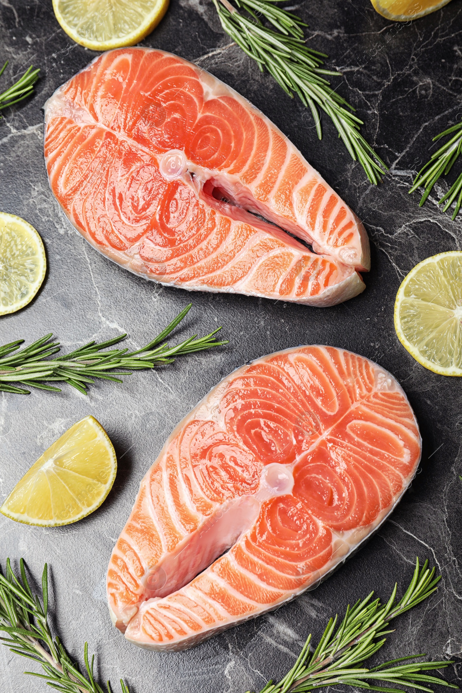 Photo of Flat lay composition with fresh raw salmon and rosemary on black marble table. Fish delicacy