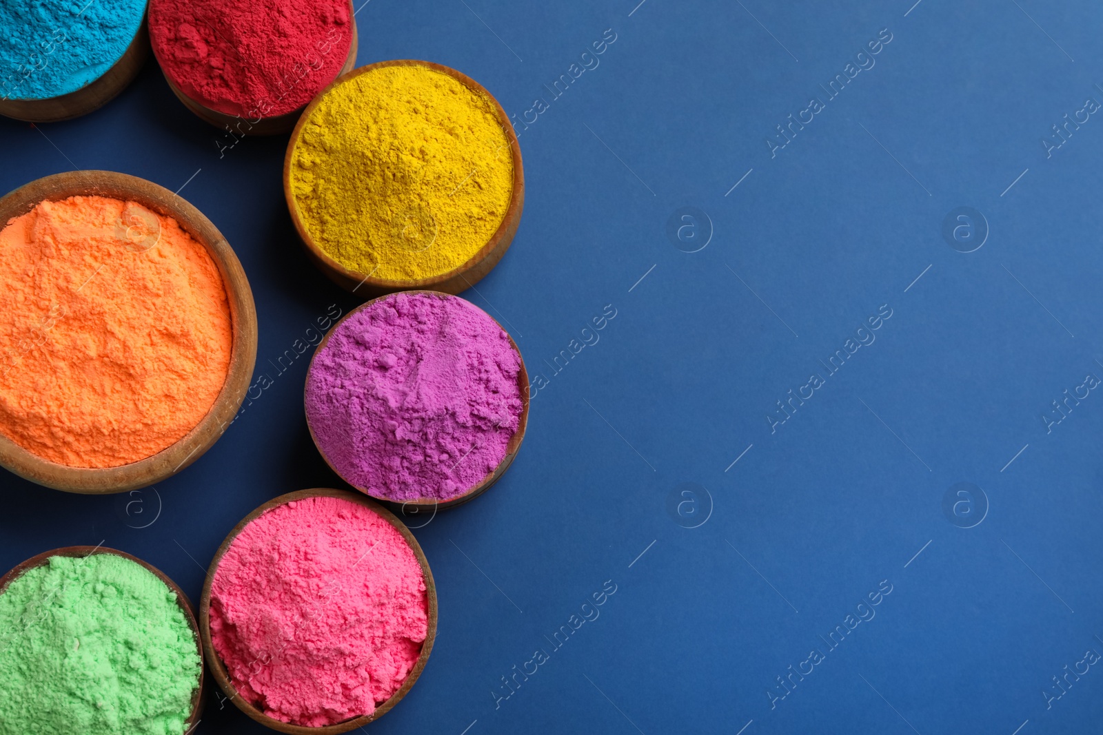 Photo of Colorful powders in bowls on blue background, flat lay with space for text. Holi festival celebration
