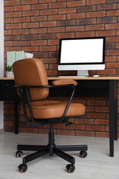 Stylish office interior with comfortable chair, desk and computer