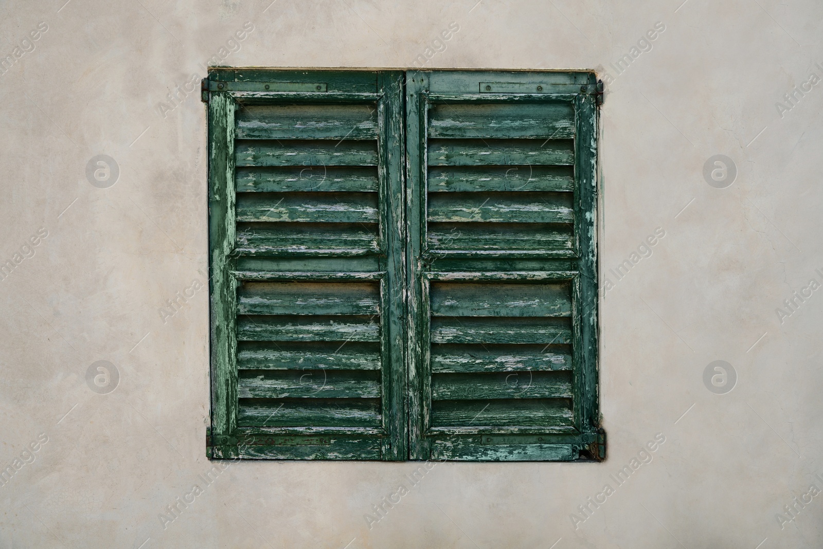 Photo of Window with old wooden shutters on concrete wall