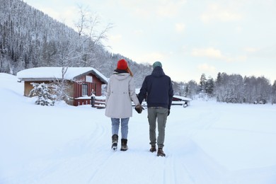 Photo of Couple walking in mountains on snowy day, back view. Winter vacation