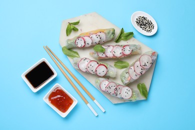 Photo of Delicious spring rolls served on light blue background, flat lay