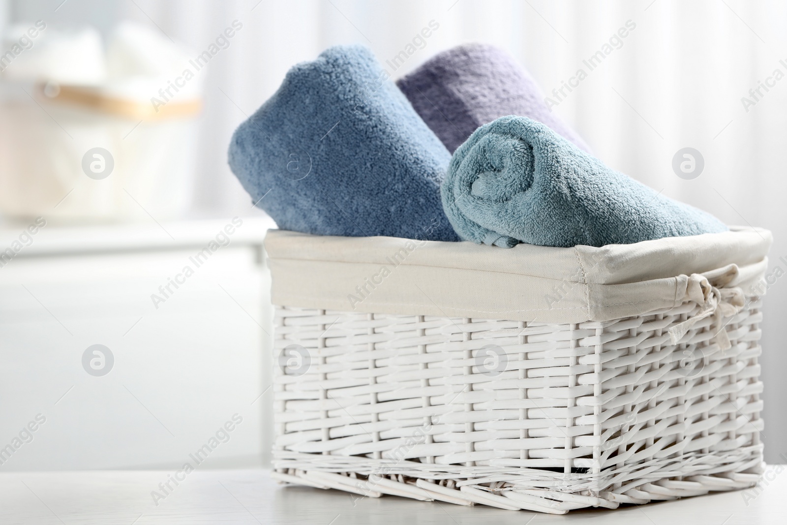 Photo of Basket of fresh towels on table. Space for text