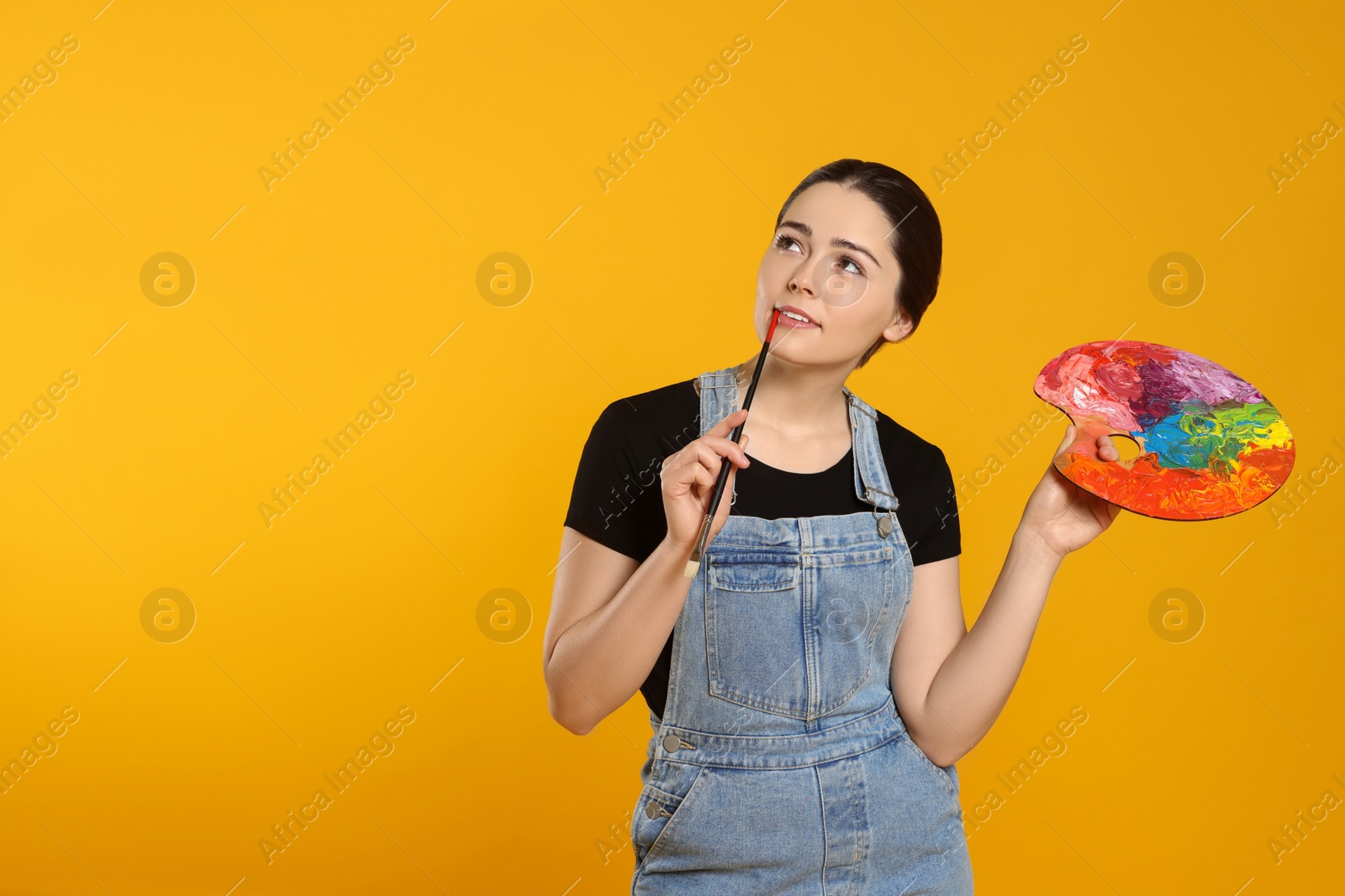 Photo of Woman with painting tools on yellow background, space for text. Young artist