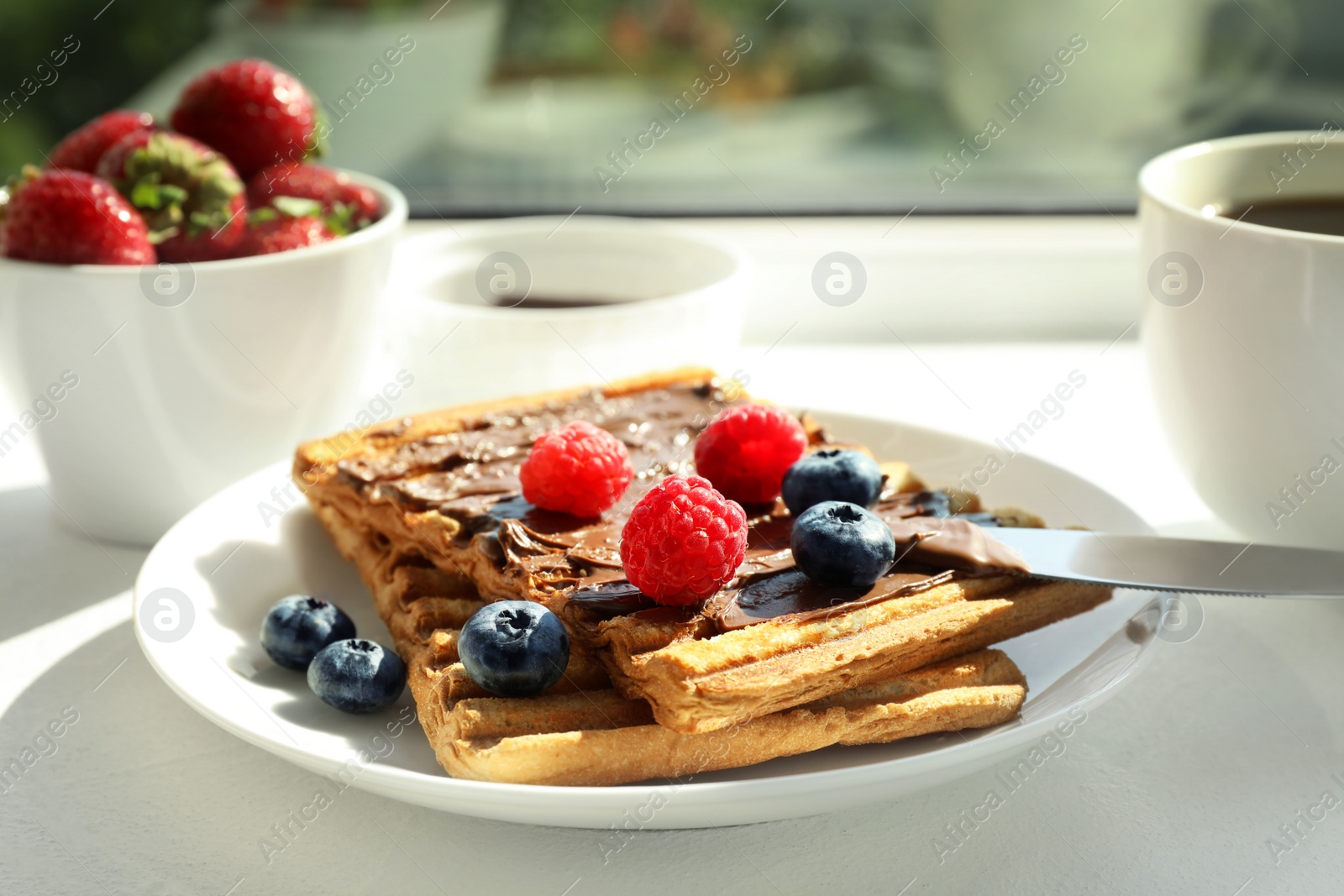 Photo of Tasty breakfast with toasts on white sunlit windowsill