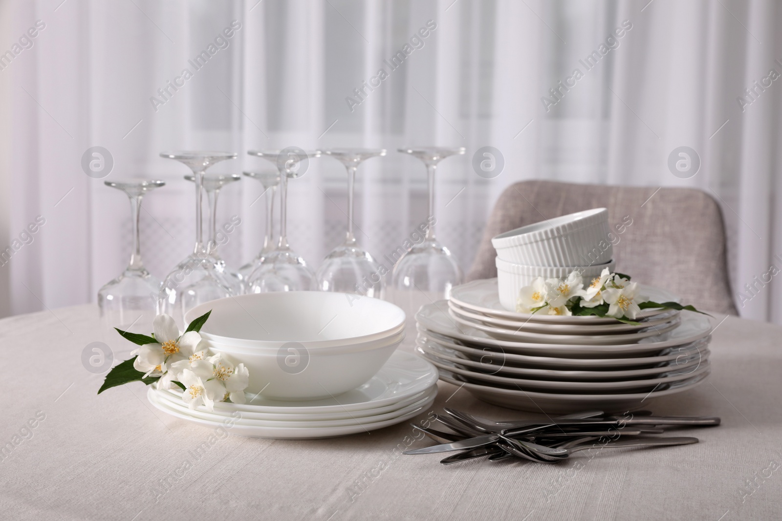 Photo of Set of clean dishware, cutlery and wine glasses on table indoors