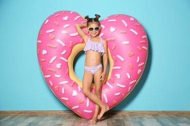 Photo of Cute little girl with inflatable heart near color wall