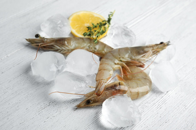 Photo of Fresh raw shrimps with ice on white wooden table