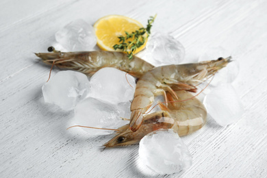 Fresh raw shrimps with ice on white wooden table