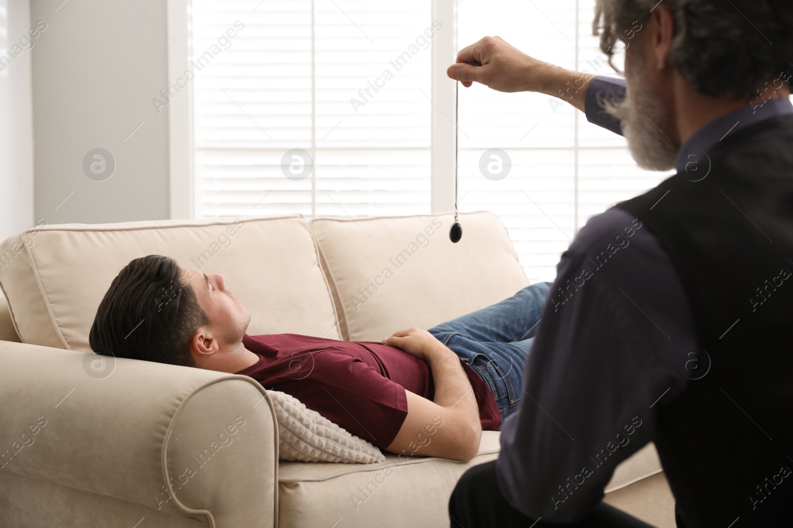 Photo of Psychotherapist using pendulum during hypnotherapy   session in office