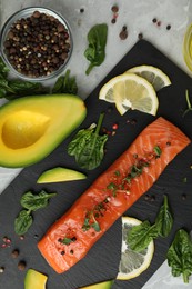 Photo of Delicious salmon served with spinach, lemon and avocado on grey marble table, flat lay