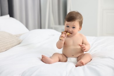 Photo of Cute baby boy with wooden rattle on bed at home. Space for text
