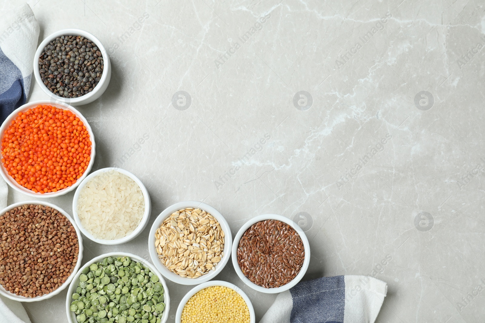 Photo of Flat lay composition with different types of legumes and cereals on grey marble table, space for text. Organic grains