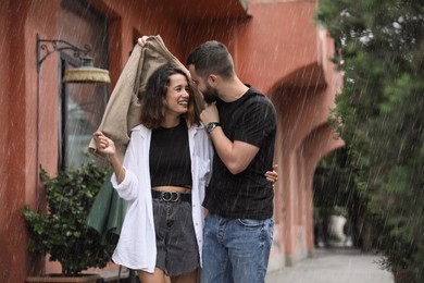 Photo of Young couple enjoying time together under rain on city street, space for text