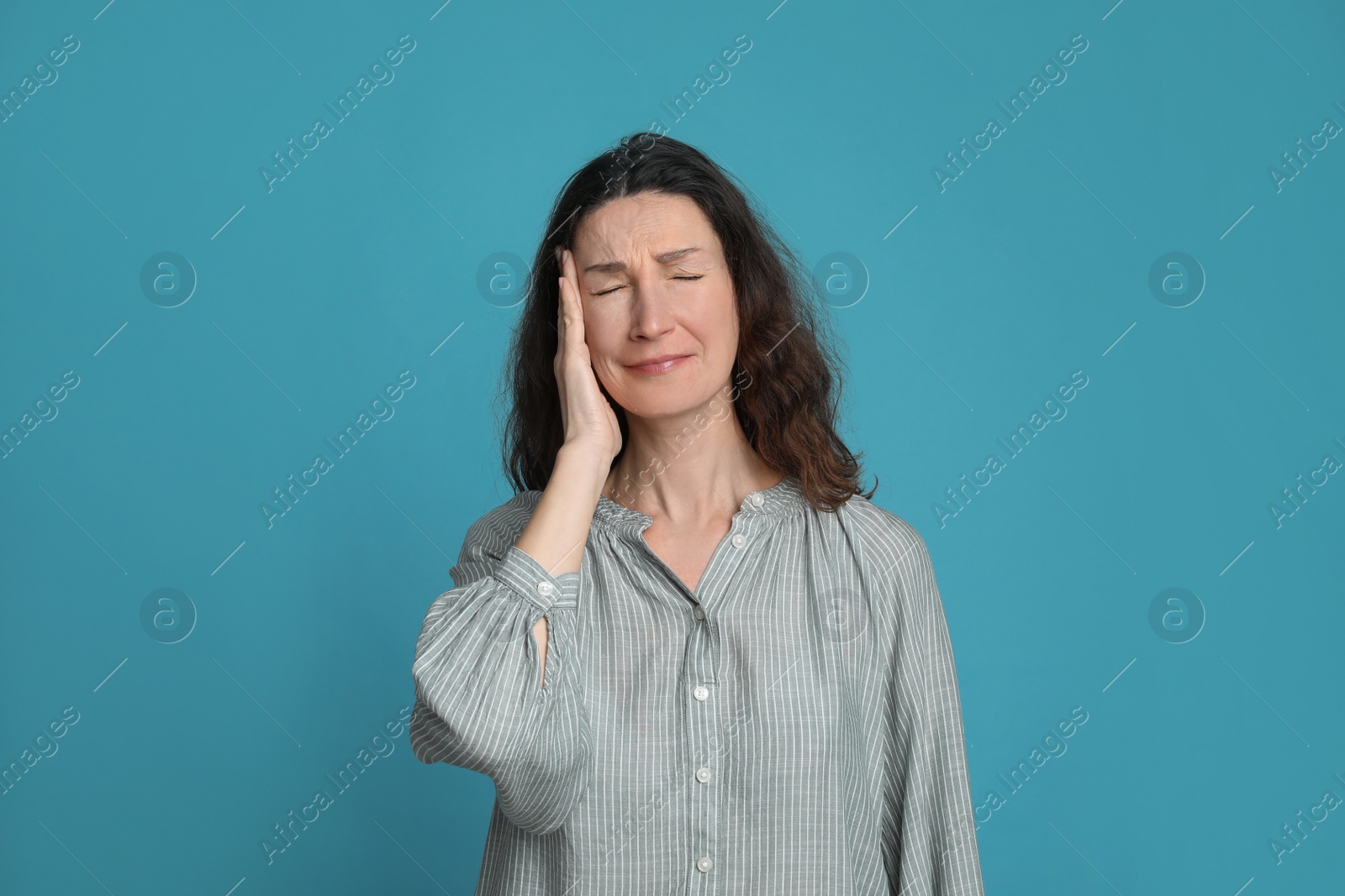 Photo of Mature woman suffering from headache on light blue background