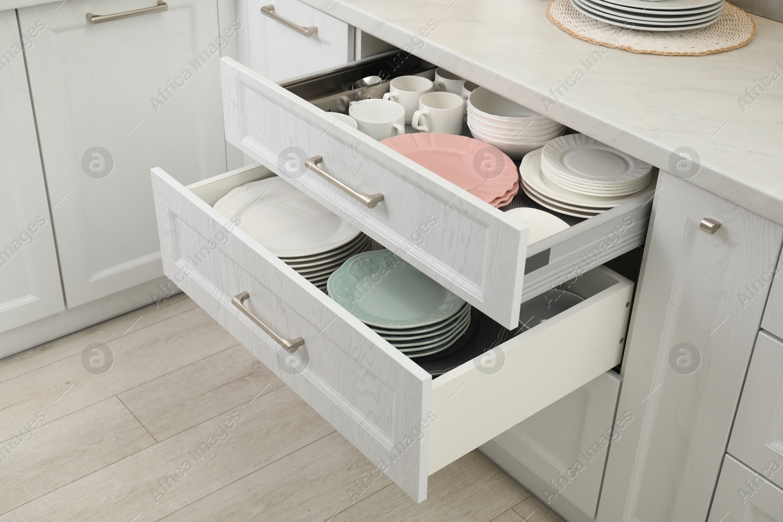 Photo of Clean plates, bowls and cups in drawers indoors