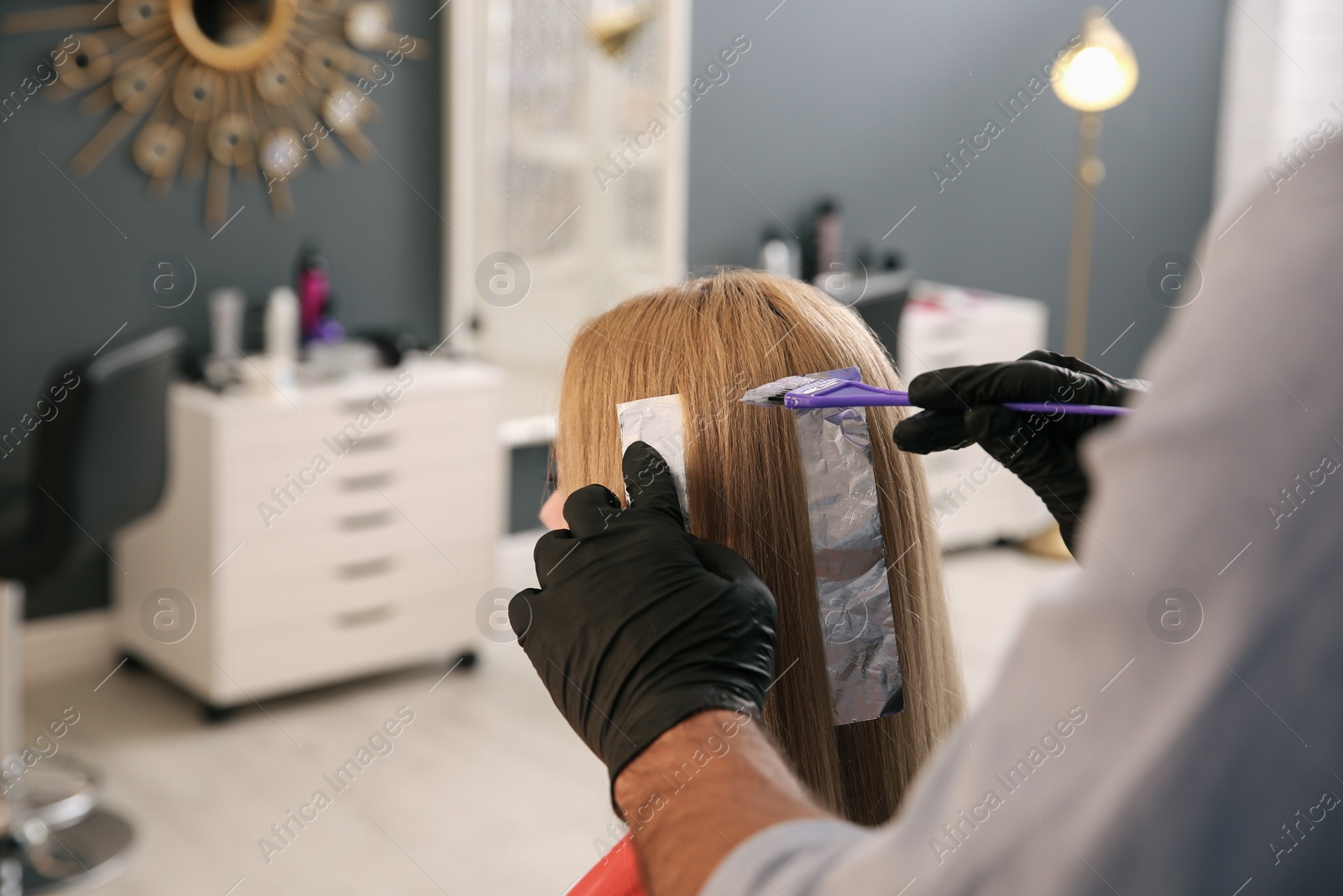 Photo of Professional hairdresser dying hair in beauty salon, closeup