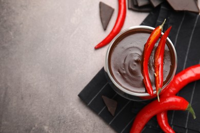 Photo of Delicious hot chocolate with chili peppers on brown textured table, flat lay. Space for text