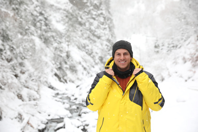 Photo of Handsome man wearing warm clothes outdoors on snowy day. Winter vacation