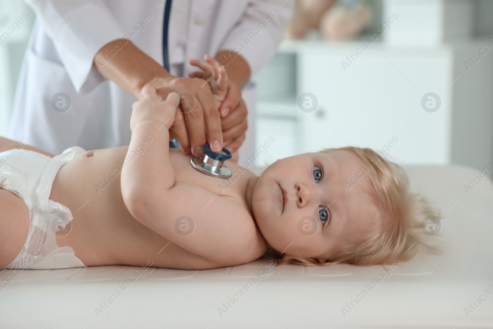 Photo of Pediatrician examining baby with stethoscope in hospital. Health care