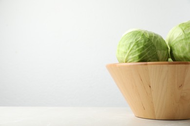 Photo of Ripe white cabbage on light marble table. Space for text