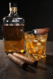 Photo of Cigars and whiskey on grey table against black background