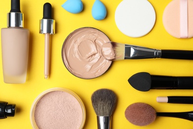 Flat lay composition with skin foundation, powder and beauty accessories on color background