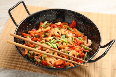 Photo of Shrimp stir fry with vegetables in wok on wooden table