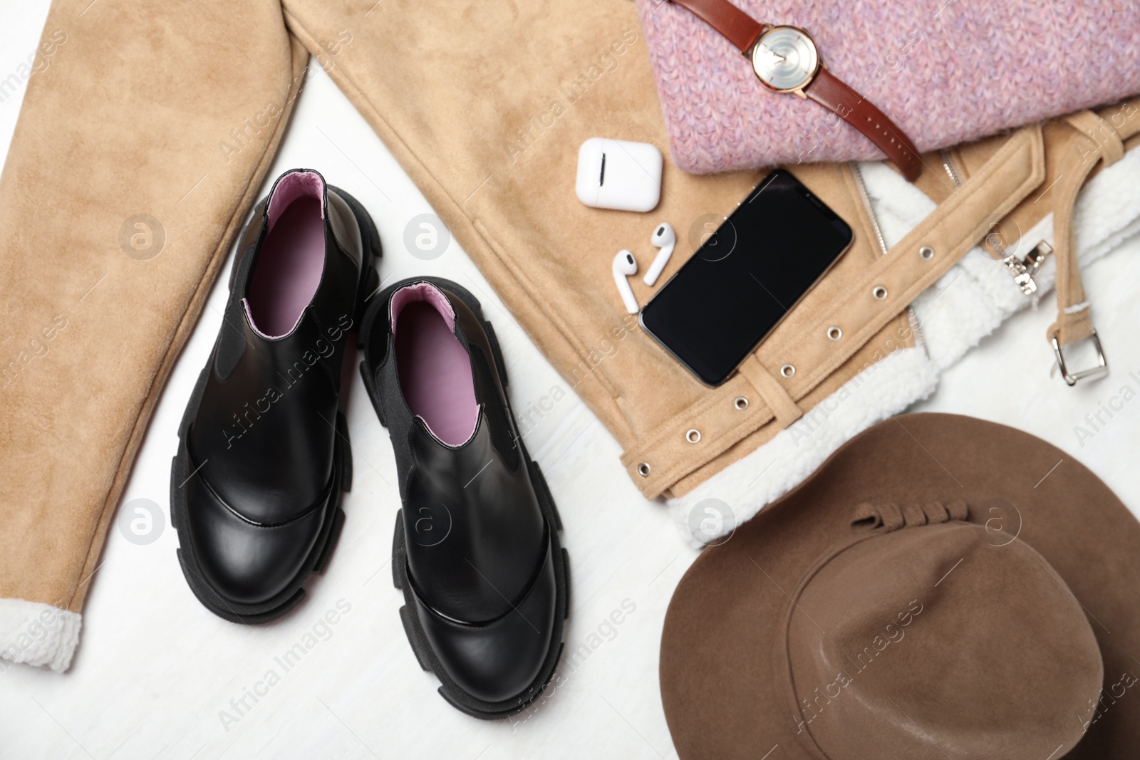 Photo of Pair of stylish leather boots, clothes and accessories on white wooden background, flat lay