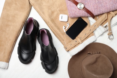 Pair of stylish leather boots, clothes and accessories on white wooden background, flat lay