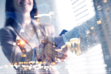 Image of Business people shaking hands and night cityscape, closeup. Double exposure