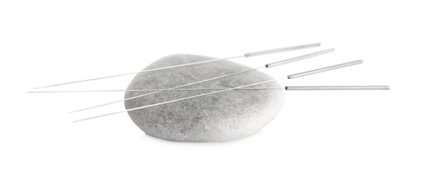 Needles for acupuncture and stone on white background