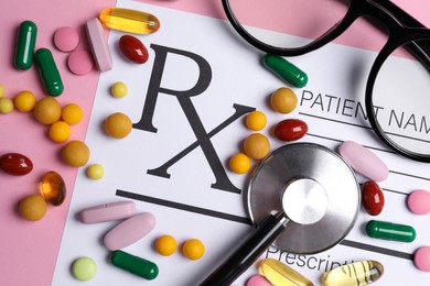 Photo of Medical prescription form, pills, glasses and stethoscope on pink background, flat lay
