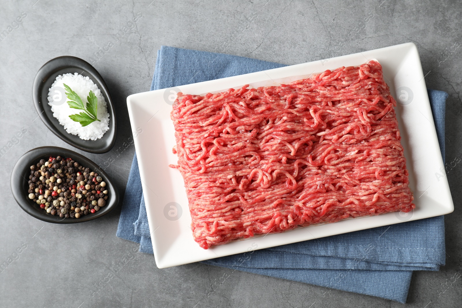 Photo of Raw ground meat and spices on grey table, top view