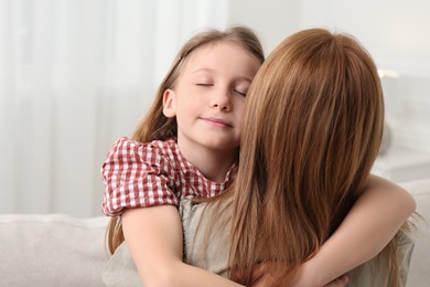 Cute daughter hugging her mom at home