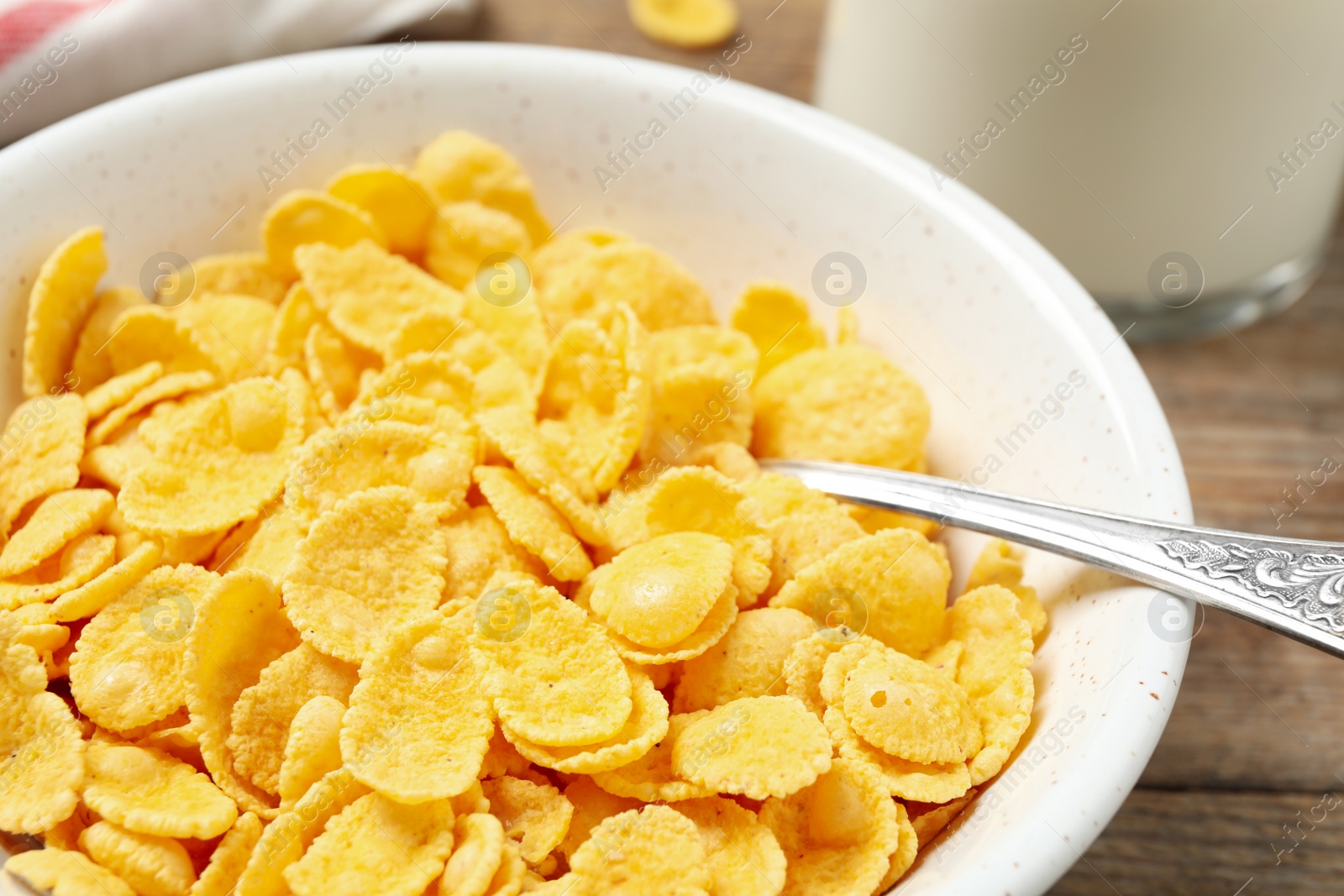 Photo of Tasty crispy corn flakes in bowl, closeup