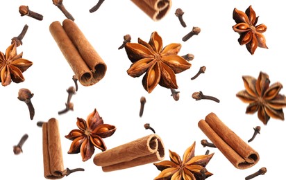 Aromatic anise stars, cinnamon and cloves falling on white background