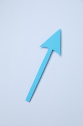 Photo of Light blue paper arrow on white background, top view